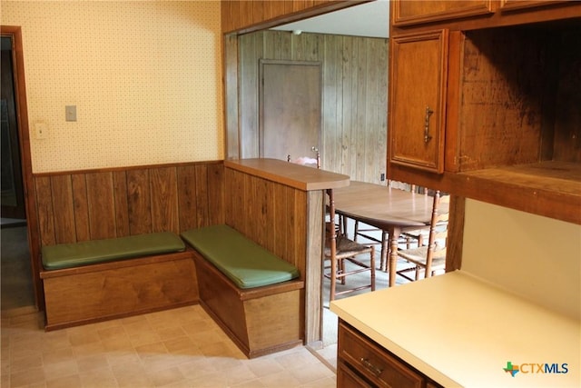 1610 Bexar Ave, Victoria, TX 77901 - kitchen featuring wallpapered walls, wainscoting, brown cabinets, wooden walls, and light countertops