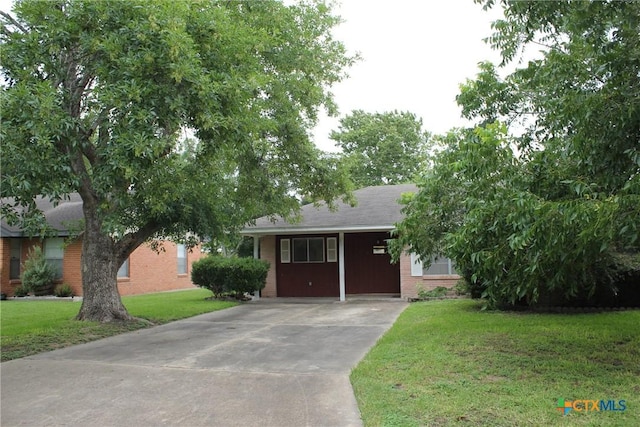 1610 Bexar Ave, Victoria, TX 77901 - view of front facade featuring brick siding, driveway, a front lawn, and a carport