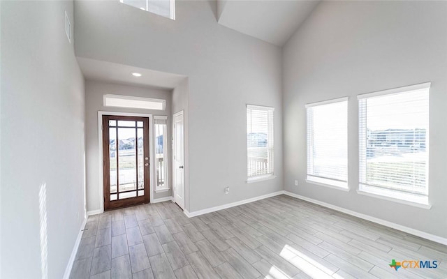 foyer entrance with light wood-type flooring and a towering ceiling