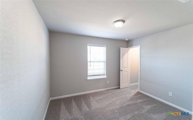 carpeted empty room featuring a textured ceiling