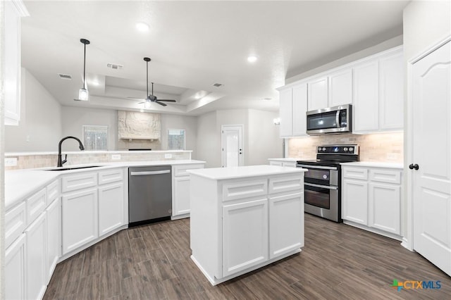 kitchen featuring a raised ceiling, white cabinetry, sink, decorative backsplash, and stainless steel appliances