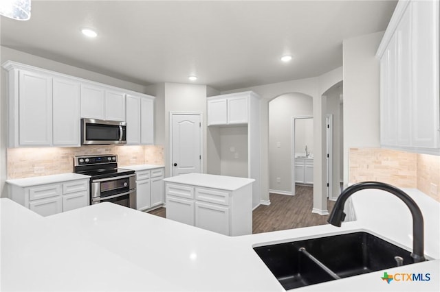 kitchen with tasteful backsplash, appliances with stainless steel finishes, sink, and white cabinets