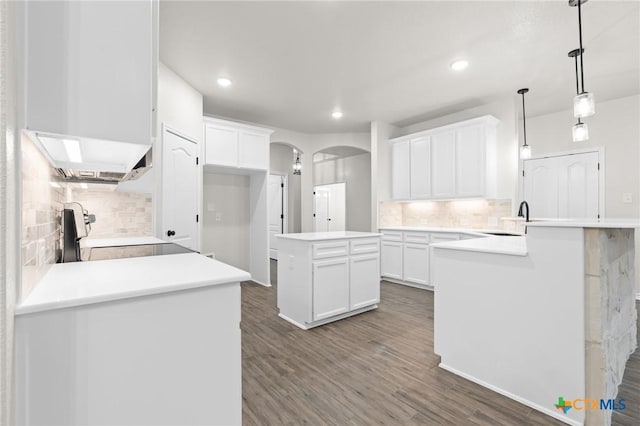 kitchen featuring dark wood-type flooring, range, decorative light fixtures, a center island, and white cabinets