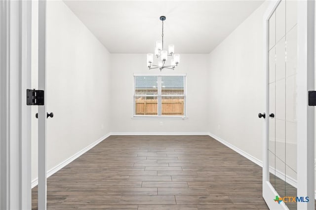 unfurnished dining area featuring dark hardwood / wood-style floors and a chandelier