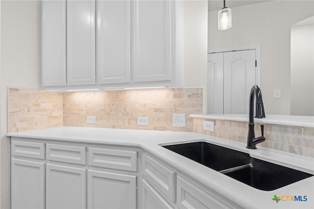 kitchen featuring hanging light fixtures, sink, and white cabinets