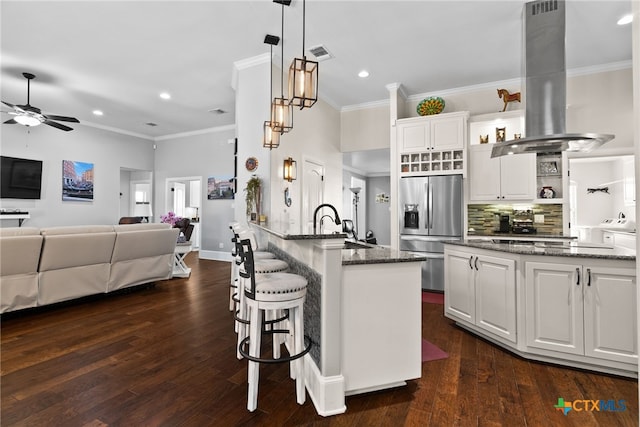 kitchen with dark stone counters, island range hood, stainless steel fridge with ice dispenser, dark hardwood / wood-style floors, and white cabinetry