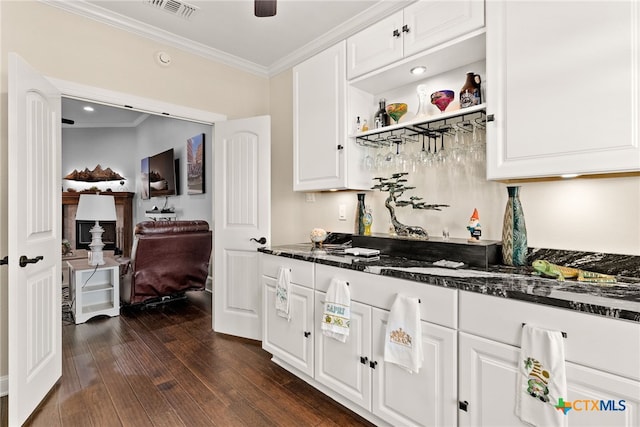 kitchen featuring white cabinets, dark stone counters, crown molding, and dark hardwood / wood-style flooring