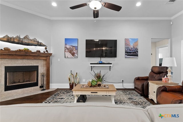 living room with hardwood / wood-style floors, ceiling fan, a tile fireplace, and ornamental molding