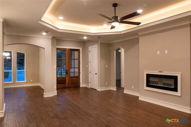 unfurnished living room featuring dark wood-type flooring, french doors, ornamental molding, a raised ceiling, and ceiling fan