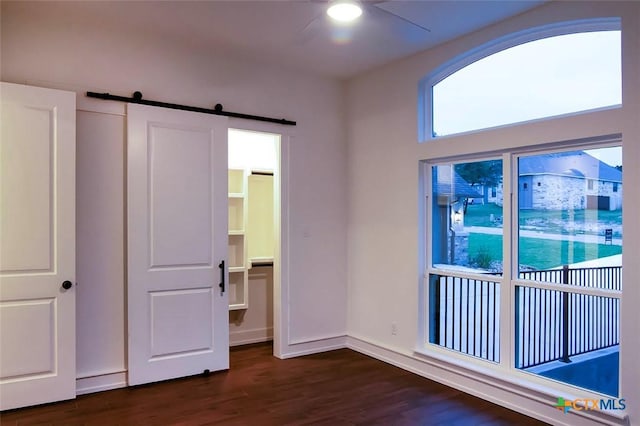 unfurnished bedroom with a barn door and dark hardwood / wood-style flooring