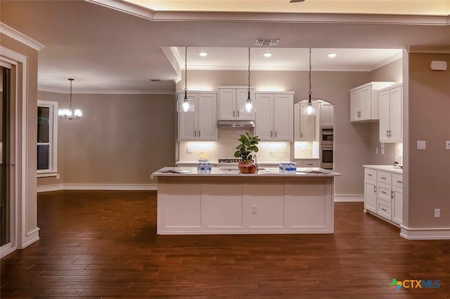 kitchen featuring white cabinetry, dark hardwood / wood-style flooring, an island with sink, and pendant lighting