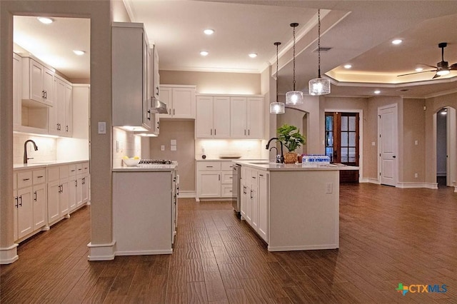 kitchen with sink, white cabinetry, decorative light fixtures, dark hardwood / wood-style flooring, and an island with sink