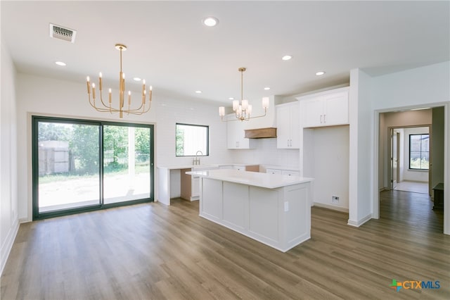 kitchen featuring an inviting chandelier, a center island, hanging light fixtures, and white cabinets