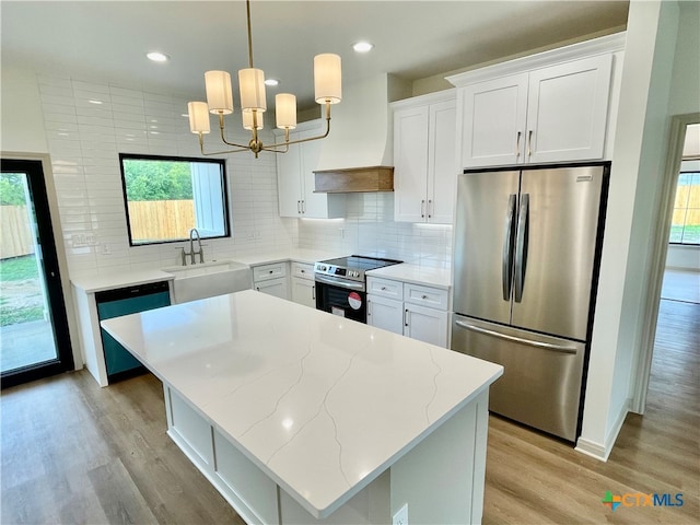 kitchen with appliances with stainless steel finishes, decorative light fixtures, tasteful backsplash, sink, and white cabinets