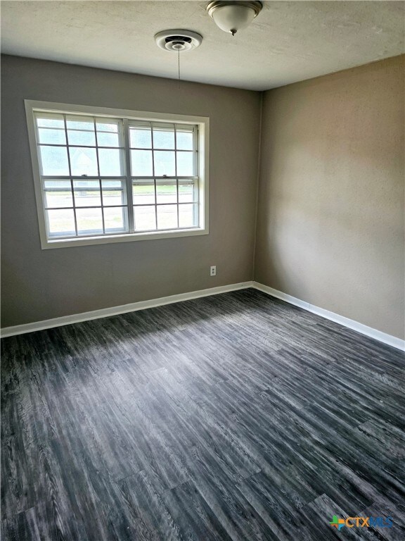 unfurnished room with dark wood-type flooring