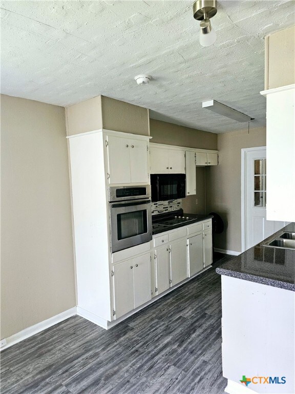 kitchen featuring white cabinetry, oven, a textured ceiling, and dark hardwood / wood-style floors