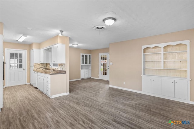 kitchen with dark wood-style floors, a sink, visible vents, white cabinetry, and baseboards
