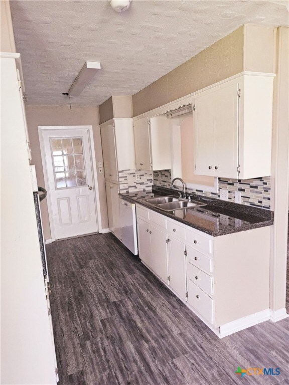 kitchen featuring white cabinets, dark hardwood / wood-style floors, dark stone countertops, and sink