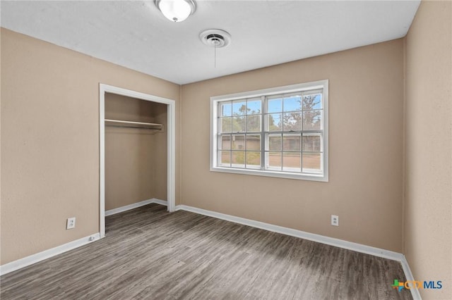 unfurnished bedroom featuring baseboards, visible vents, wood finished floors, and a closet
