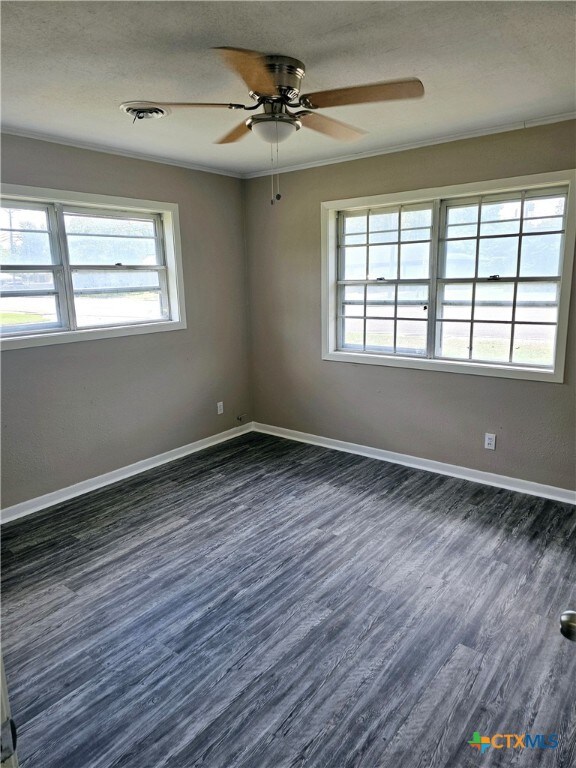 empty room with dark hardwood / wood-style flooring, ceiling fan, and crown molding