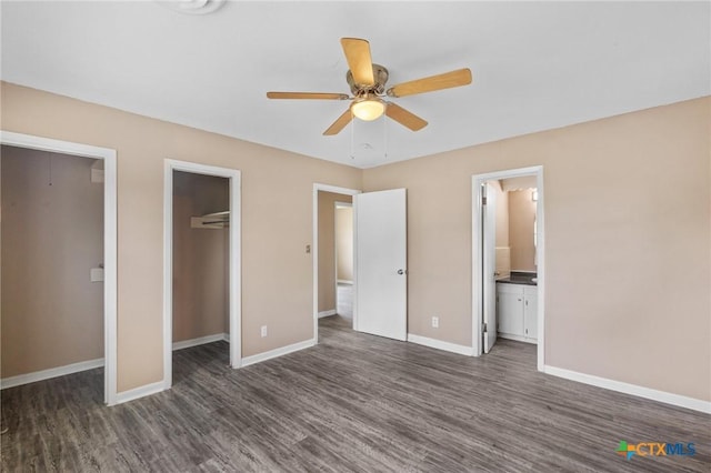 unfurnished bedroom with ensuite bathroom, baseboards, and dark wood finished floors