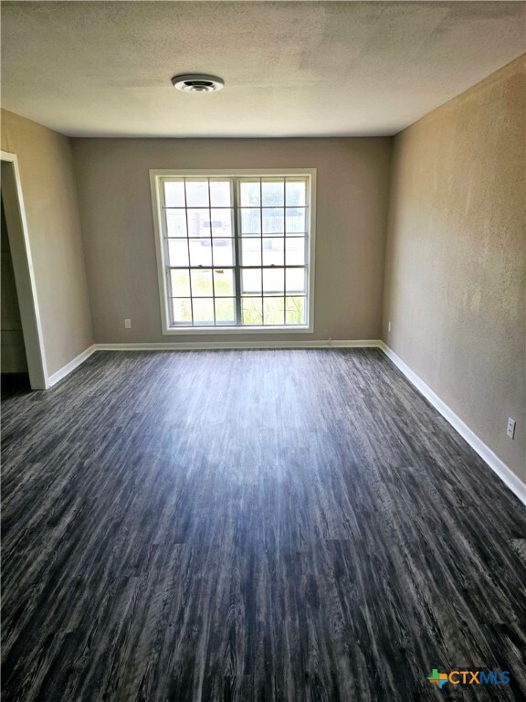 empty room featuring dark hardwood / wood-style flooring and a textured ceiling