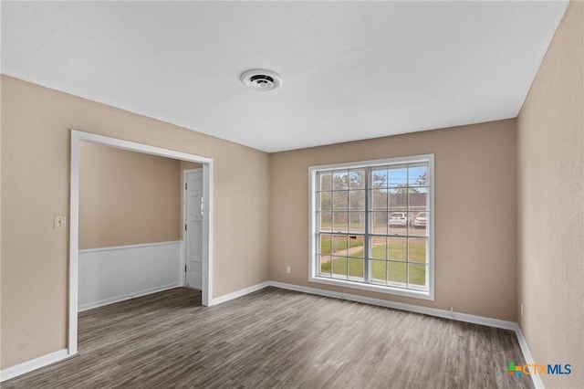 unfurnished room with wood finished floors, visible vents, and baseboards