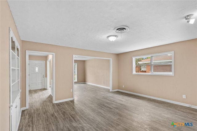 spare room featuring baseboards, visible vents, and wood finished floors