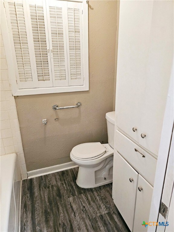 bathroom featuring toilet, a bath, and hardwood / wood-style flooring