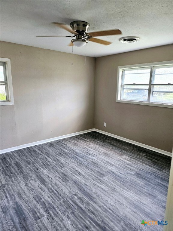 unfurnished room with dark wood-type flooring and ceiling fan