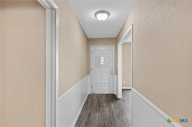 entryway with a wainscoted wall, dark wood-style flooring, and a textured wall