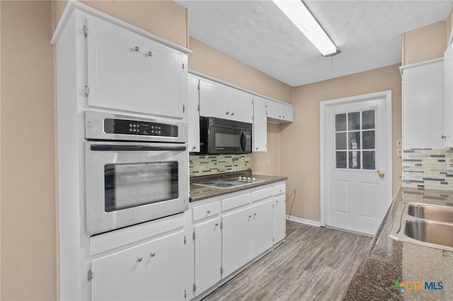 kitchen featuring black microwave, backsplash, electric stovetop, and oven