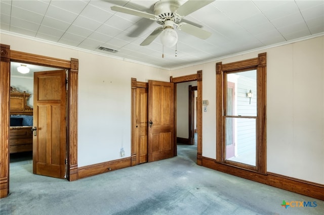 carpeted spare room featuring ceiling fan and crown molding