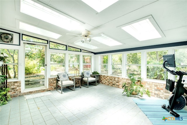 sunroom featuring lofted ceiling with skylight, ceiling fan, and a healthy amount of sunlight