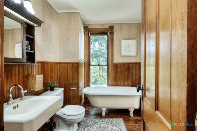 bathroom featuring wood-type flooring, crown molding, a bath, wooden walls, and toilet