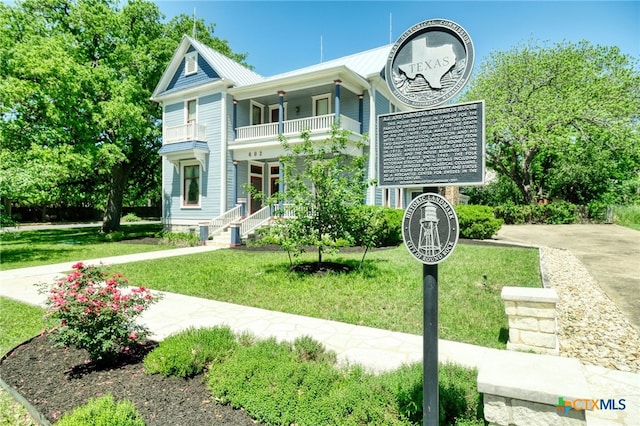 view of front facade with a porch, a front lawn, and a balcony