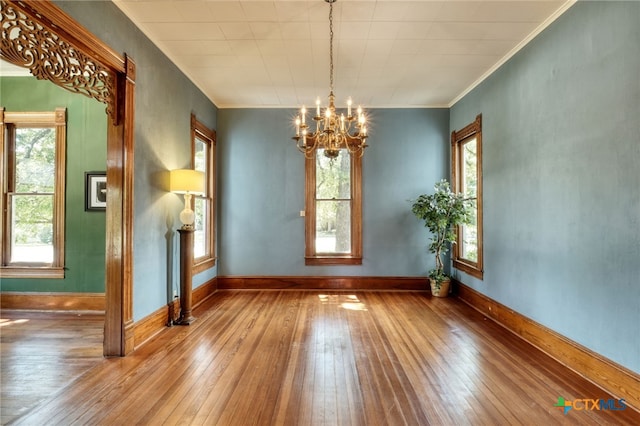 unfurnished room with ornamental molding, wood-type flooring, and a notable chandelier