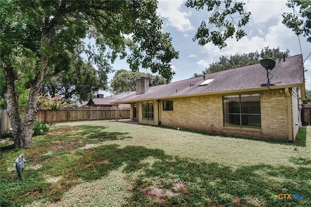 505 Bramble Bush Ln, Victoria, TX 77904 - back of house featuring brick siding, a fenced backyard, a chimney, and a shingled roof