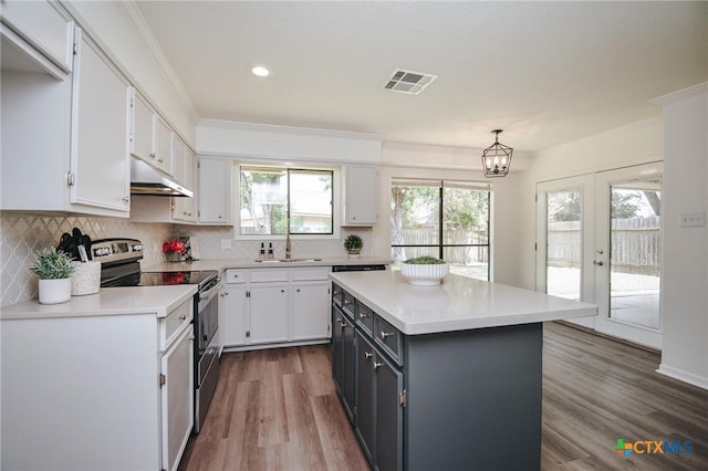 505 Bramble Bush Ln, Victoria, TX 77904 - kitchen with stainless steel range with electric stovetop, under cabinet range hood, white cabinets, light countertops, and crown molding