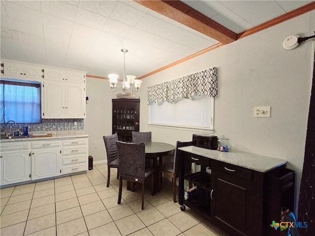 tiled dining area featuring crown molding, sink, and a notable chandelier