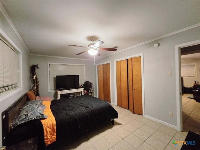 bedroom featuring crown molding, two closets, ceiling fan, and light tile patterned floors