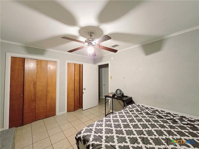 bedroom featuring crown molding, ceiling fan, light tile patterned floors, and two closets