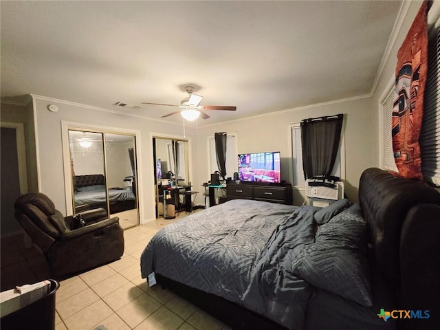 bedroom with crown molding, two closets, ceiling fan, and light tile patterned floors