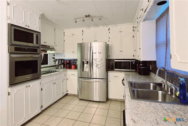 kitchen with stainless steel appliances, sink, light tile patterned floors, and white cabinets