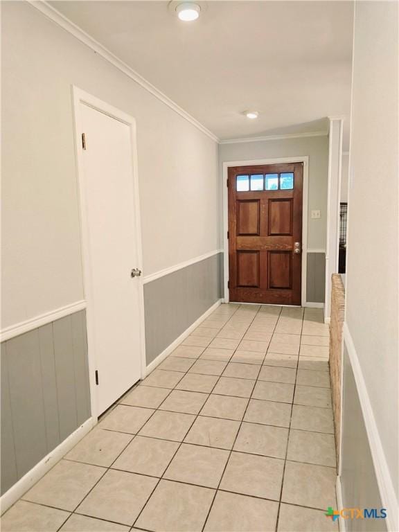 foyer with crown molding and light tile patterned floors