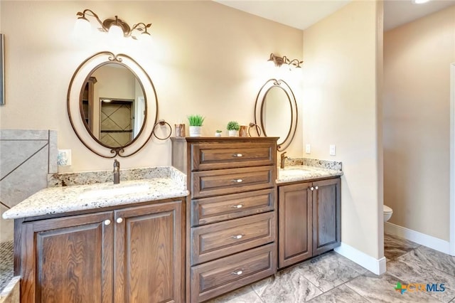 full bathroom with baseboards, a sink, toilet, and double vanity