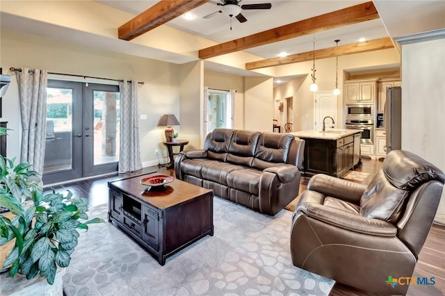 living room featuring a ceiling fan, baseboards, french doors, light wood-type flooring, and beamed ceiling