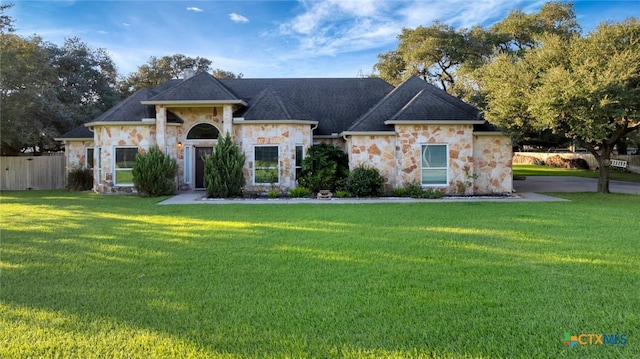 62 Grand Oak Dr, Inez, TX 77968 - view of front facade with stone siding, roof with shingles, a front yard, and fence