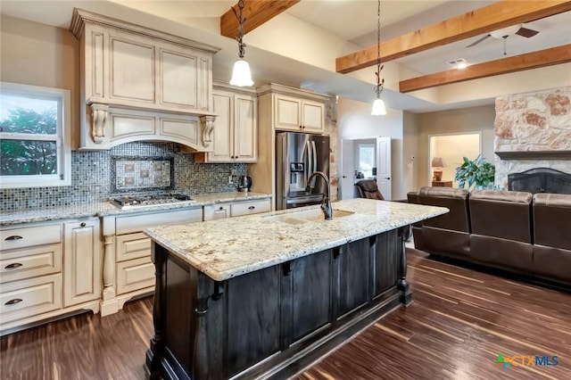 kitchen with a center island with sink, appliances with stainless steel finishes, open floor plan, hanging light fixtures, and a sink