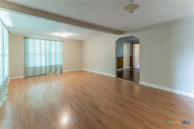 empty room with hardwood / wood-style floors and beamed ceiling